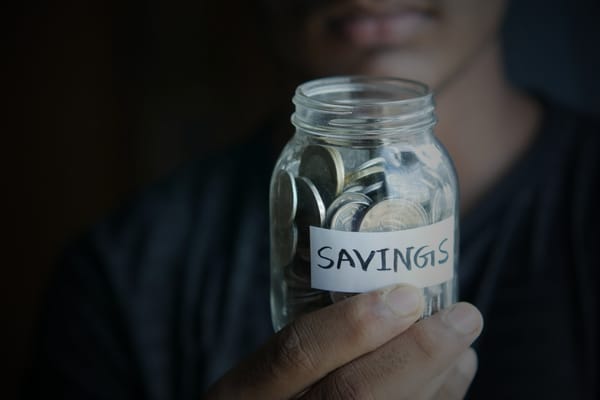 A person holding up a savings jar with coins inside